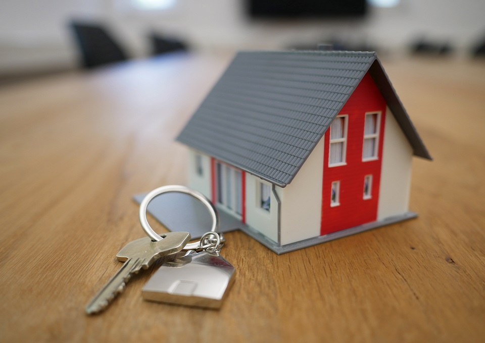 Image of a small model home on a table next to keys.